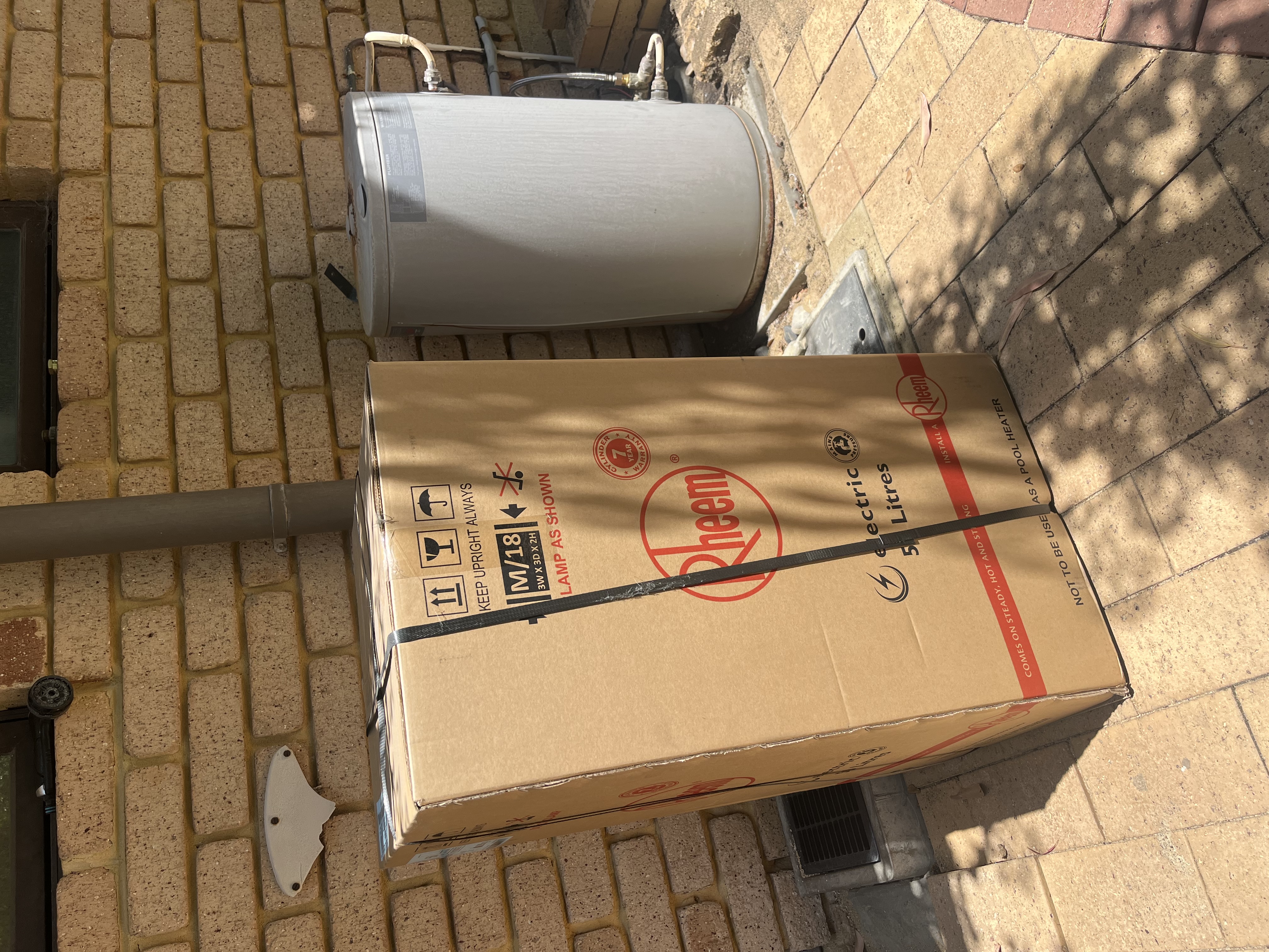 Rheem electric hot water system ready for installation beside an older unit